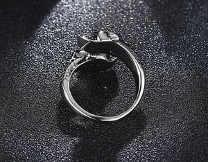 Detailed close-up of a vintage silver skull ring with punk industrial carvings on black sand