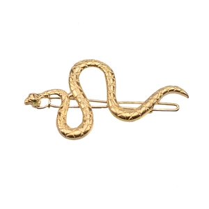 Macro shot of a golden snake hair clip with green eyes and detailed scale texture
