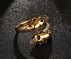 Macro detail of antique gold double skull ring with intricate metal carvings and adjustable band