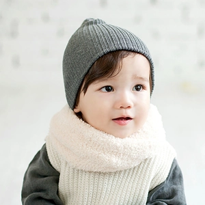 Détail du bonnet en tricot gris rayé et du tour de cou en polaire crème pour bébés