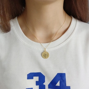 Elegant gold coin pendant necklace with embossed vintage figure on a thin link chain