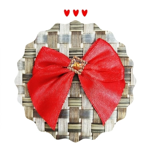 Detail of red satin bow accessory featuring a central amber crystal with rhinestone trim