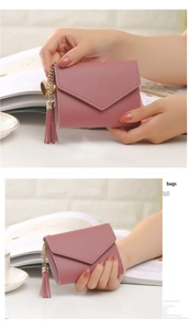 Close-up of dusty rose leather wallet featuring envelope flap and heart tassel detail