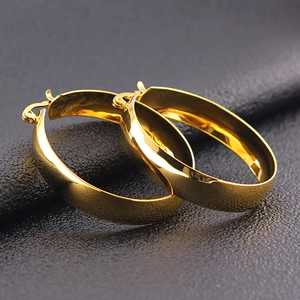 Minimalist wide gold hoop earrings with polished finish on black textured background
