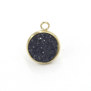 Macro detail of round gold stainless steel pendant with black sparkling resin inlay