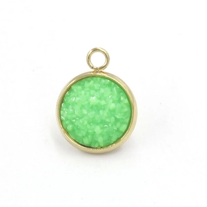 Macro shot of a round green resin pendant with a gold stainless steel frame and ring