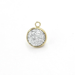 Close-up of a gold round pendant with silver glitter resin inlay and jump ring detail