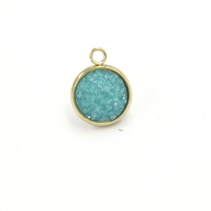 Macro detail of 12mm gold stainless steel charm with teal resin crystal inlay for jewelry