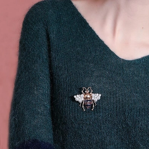 Detail of a vintage honey bee brooch with pearls on a dark green knitted sweater