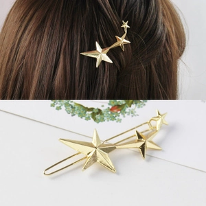 Detail view of gold alloy star hair clip showing model wear and geometric metal design