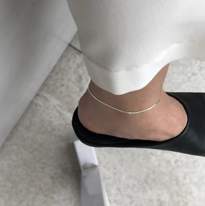 Close-up of minimalist S925 sterling silver blade chain anklet worn on model ankle