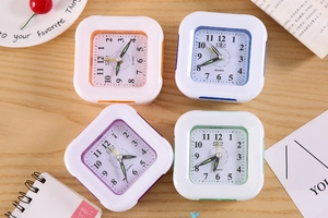 Top view of four colorful square quartz alarm clocks in orange, blue, purple, and green