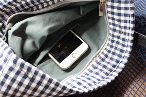 Internal view of blue gingham canvas bag showing olive green lining and storage pocket