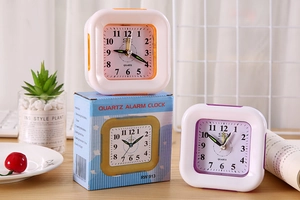 Close-up of minimalist square plastic alarm clocks in orange and purple with packaging