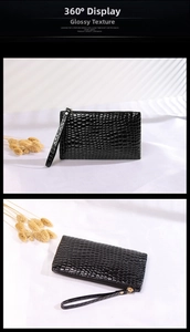Detail of black crocodile texture clutch bag with wristlet strap and golden zipper
