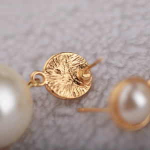 Detailed macro view of the textured gold metal base and earring pin with large white pearl