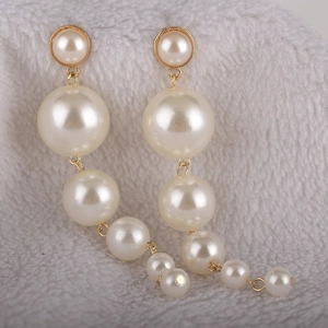 Elegant long cascading white pearl drop earrings with gold metal accents on plush background