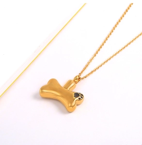 Detailed view of a gold bone-shaped pet memorial pendant with a black paw print charm