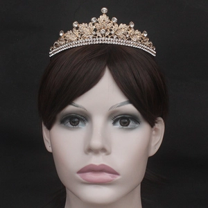 Close-up of golden bridal crown with white rhinestones and leaf pattern on a model