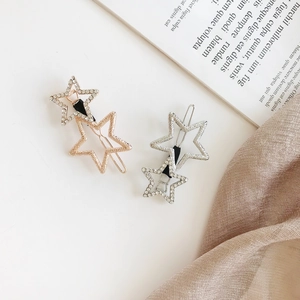 Close-up of gold and silver hollow star hair clips with shimmering rhinestone inlay