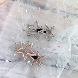Close-up of silver and rose gold star hair clips with rhinestones on white tulle