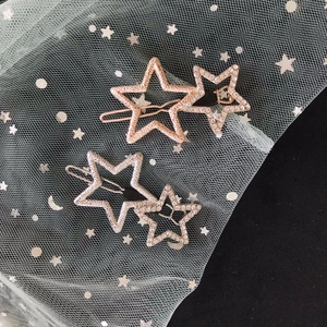 Close-up of gold and silver star hair pins with sparkling rhinestones on green tulle