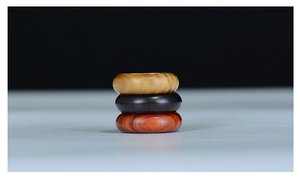 Detailed view of three minimalist natural wood rings in light, dark, and reddish brown tones