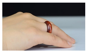 Classic mahogany wood ring with natural grain shown on finger in a minimalist style