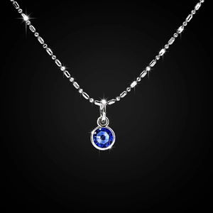 Detail of silver bead chain necklace with a faceted blue stone pendant in bezel setting