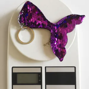 Detailed view of purple mermaid tail sequin keychain showing 8g weight on a scale