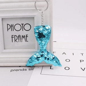Detail of blue mermaid tail keychain with reflective double-sided sequins and silver ring