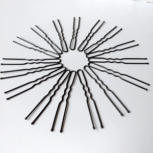Disposition radiale d'épingles à cheveux en forme de U en métal noir sur fond blanc
