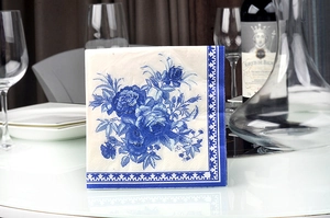 Detail view of paper napkins with blue floral patterns and geometric borders on a table