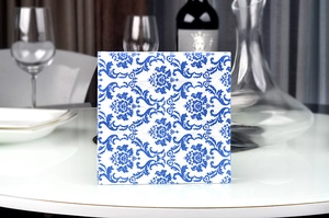 Close-up of square blue damascus pattern napkins stacked on a white restaurant table