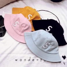 Flat lay of four colorful cotton fisherman hats with white letter S embroidery detail