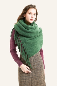 Vista detallada de una bufanda de punto verde gruesa con borlas en una modelo femenina