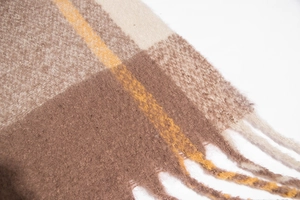 Close-up of thick checkered scarf with tassel detail in brown and beige wool-like texture