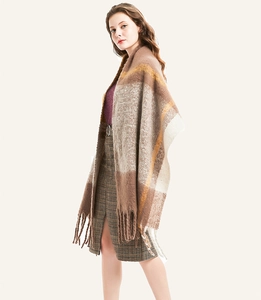 Close-up of thick plaid scarf texture with oversized tassels in brown and beige tones