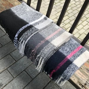 Detail shot of thick plaid scarves with tassels on a wooden bench outdoors