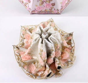 Detailed view of pink floral embroidery and lace borders on a triple-fold sun umbrella