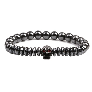 Bracelet punk en perles d'hématite avec crâne en cuivre et yeux en zircon rouge sur fond blanc