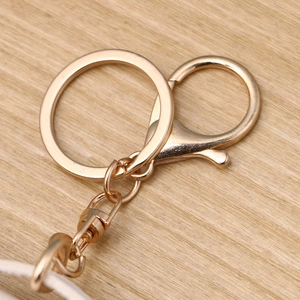 Polished gold metal keychain accessory with lobster clasp and round keyring on wood background