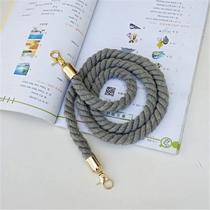 Detail of grey twisted shoulder strap with gold lobster clasps on plain background