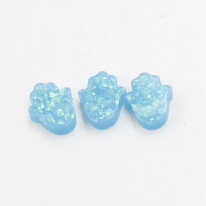 Detailed macro view of three blue opal Hamsa Hand pendants with sparkling texture