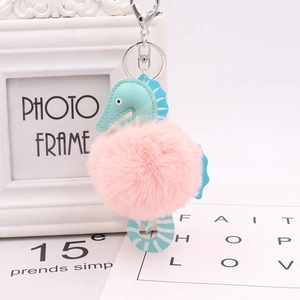 Close-up of seahorse keychain with turquoise PU leather and soft pink pom pom detail