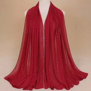 Détail d'une écharpe en mousseline rouge foncé avec strass sur un mannequin blanc