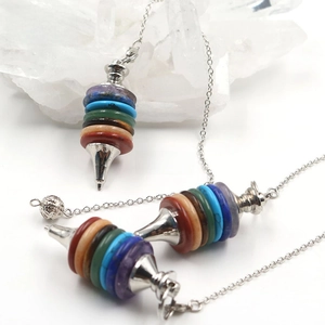 Macro detail of natural rainbow chakra crystal pendulum with metallic tip and chain
