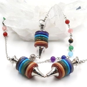 Macro shot of seven chakra crystal stones pendulum with silver metal cone for meditation