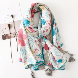 Détail de l'imprimé floral tropical et des franges à pompons gris sur châle en coton