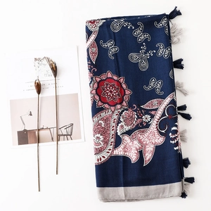 Détail d'un châle en lin bleu foncé avec motifs paisley floraux et pompons à franges